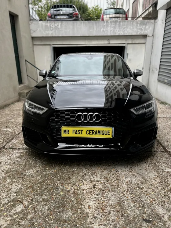 Audi RS3 noire devant l’atelier
