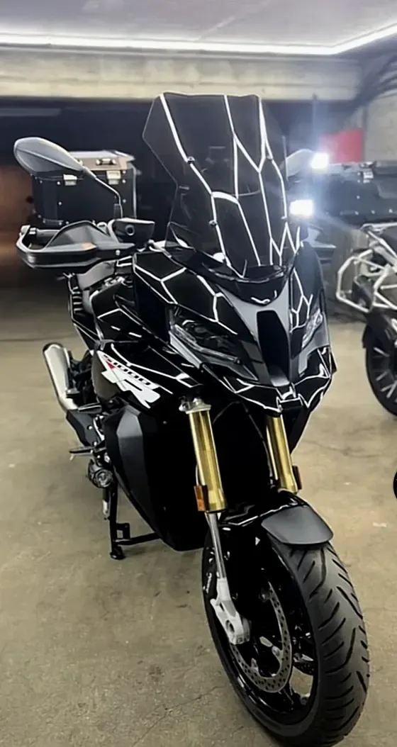 Moto BMW S1000XR noire et or sous le plafond LED de l’atelier